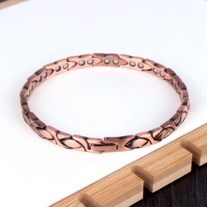Makro-Detail von Kupfer-Magnetarmband mit blattförmigen Gliedern und grauen Magneten