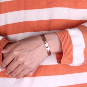 Copper magnetic therapy bracelet with leaf-shaped links worn on a woman's wrist