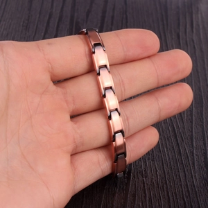 Détail d'un bracelet magnétique en or rose et noir présenté sur la paume d'une main