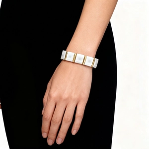 Detail of white faceted ceramic links and gold metal bars on a modern magnetic bracelet