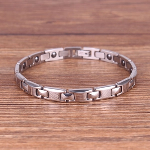 Minimalist silver magnetic stainless steel chain bracelet on a rustic wood background