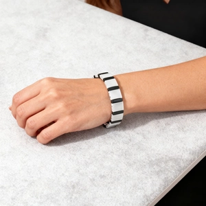 Detail view of a minimalist black and white geometric ceramic link bracelet on wrist