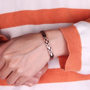 Vintage Kupferarmband mit schwarzen geometrischen Mustern, getragen von einem Modell