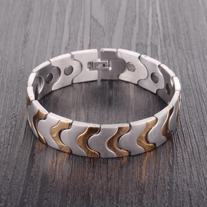 Macro view of wide gold and silver magnetic steel bracelet with engraved fold-over clasp