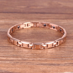 Elegant rose gold magnetic therapy bracelet on a warm wooden background for women