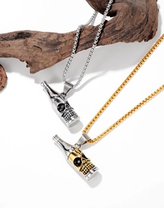 Détail des pendentifs bouteille tête de mort en argent et or sur branche en bois