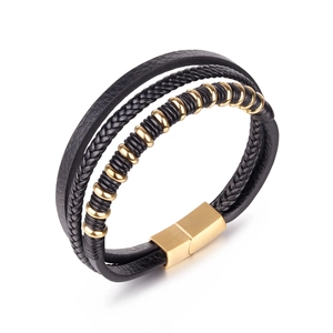 Detail of multi-layer black braided leather bracelet with golden magnetic clasp