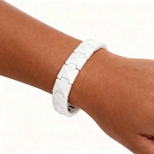 Close-up of a white geometric ceramic bracelet with pyramid-shaped links on wrist