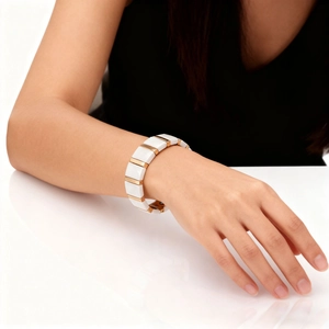 Detail of white ceramic and gold metal link bracelet worn on a female wrist