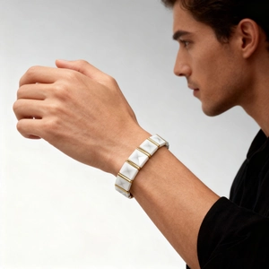 Close-up of a white pyramid link ceramic bracelet with gold metal spacers on the wrist