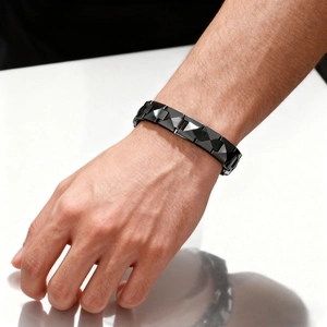 Detailed view of black geometric ceramic link bracelet worn on a male wrist