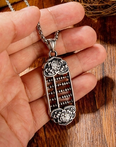 Macro shot of vintage steel abacus pendant with Fu characters on wood background