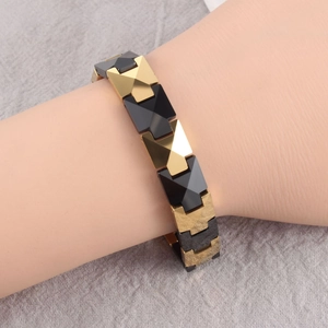Close-up of geometric ceramic and gold metal links on a magnetic therapy bracelet