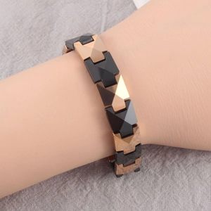 Detail of geometric X-link ceramic bracelet in matte black and rose gold finish