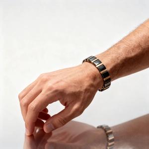 Close-up of black ceramic and gold metal link bracelet worn on male wrist