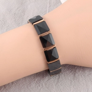 Detail of trendy black ceramic pyramid bracelet with rose gold metal accents on wrist