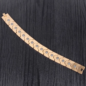 Macro view of wide golden magnetic energy bracelet with S-links and grey therapy magnets