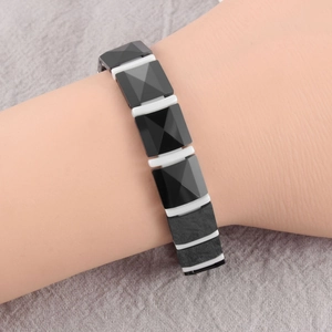 Close-up of geometric black ceramic bracelet with white spacers on a wrist
