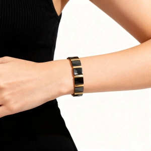 Detailed view of luxury black ceramic and gold metal link bracelet on model arm
