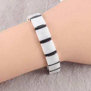 Detail shot of white geometric ceramic link bracelet with black cylindrical spacers