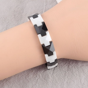 Detail of minimalist geometric ceramic bracelet with black and white links on a model wrist