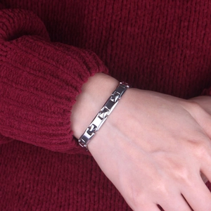 Close-up of polished silver metal bracelet worn on wrist against a red knit sweater