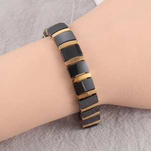 Close-up of black and gold link bracelet with ceramic magnetic modules on a wrist