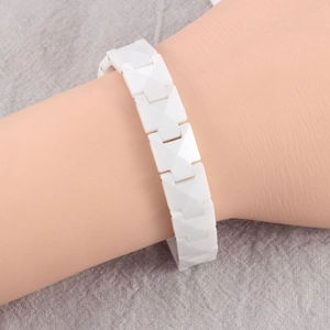 Close-up of white geometric ceramic link bracelet with pyramid facets on a model's wrist