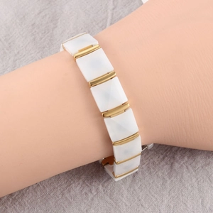 Close-up of white ceramic diamond-cut tiles and gold metal links on a magnetic bracelet