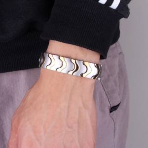 Close-up of a gold and silver magnetic energy bracelet worn on a man's wrist