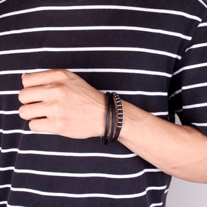 Detail of multilayer black leather bracelet featuring woven rope and silver metal beads