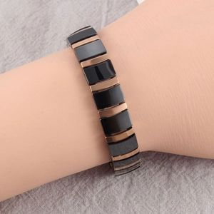 Detail of black ceramic and rose gold metal segmented bracelet on grey fabric background