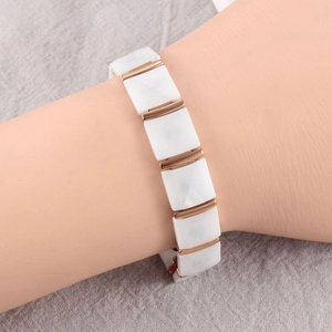 Macro detail of a white ceramic geometric link bracelet with rose gold metal connectors