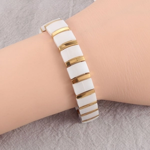 Detailed shot of a ceramic link bracelet in white and gold on a model's wrist