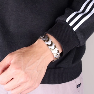 Detail of wide gold and silver magnetic therapy energy bracelet worn on a male wrist
