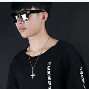Close-up of golden inverted cross pendant necklace for men on black clothing