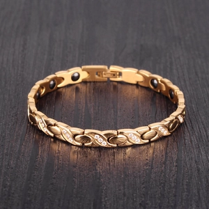 X-shaped twisted gold magnetic bracelet for women with inlaid zircons on a wooden surface