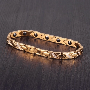 Detail of rose gold X-shaped bracelet showing inlaid white crystals and magnetic beads