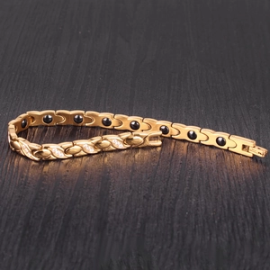 Detailed close-up of gold-plated twisted X bracelet with crystals and magnetic stones