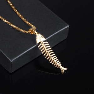 Détail d'un collier pendentif arête de poisson doré avec un design de squelette détaillé