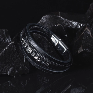 Detail of men's layered leather bracelet with stainless steel compass buckle on black stones