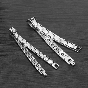 Polished stainless steel magnetic therapy bracelets on dark wood surface in diagonal layout