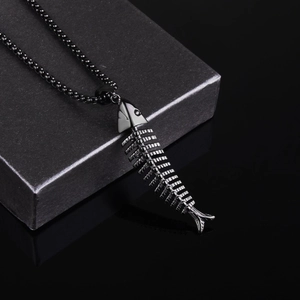 Détail du pendentif arête de poisson noir mat sur chaîne à billes avec reflet élégant