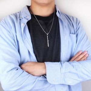Gros plan d'un collier pendentif dague argentée avec chaîne à billes sur un mannequin homme