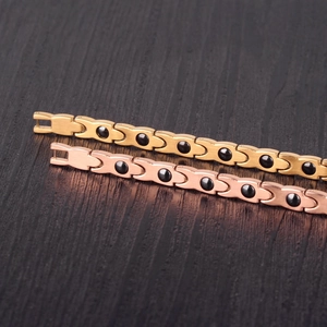 Close-up of twisted X-shape bracelets with black stones in gold and rose gold finish