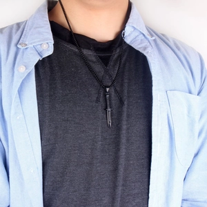 Gros plan d'un collier avec pendentif poignard noir tactique porté par un mannequin homme hip-hop