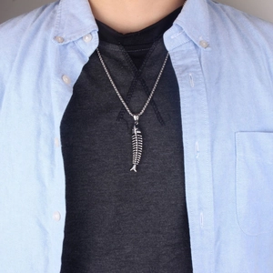 Collier pendentif arête de poisson pour homme en acier titane porté sur chemise bleue