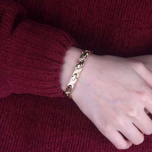 Detail of rose gold X-shaped twisted bracelet with zircon inlay on female wrist