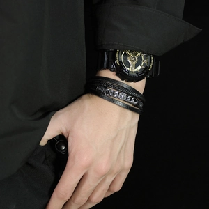 Close-up of men's multi-layer braided leather bracelet with silver compass and metal chain