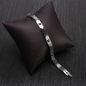 Minimalistisches Edelstahlarmband mit schwarzen Magneten auf braunem Lederkissen
